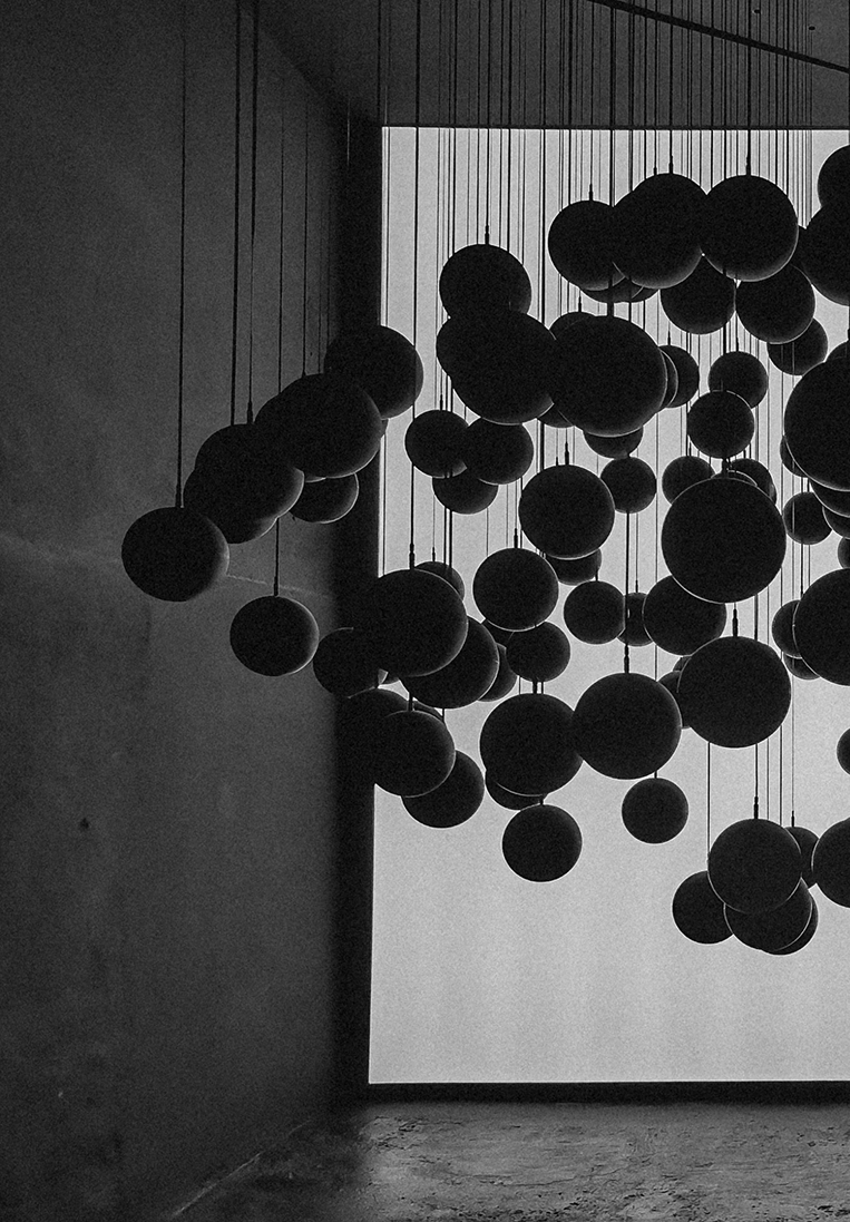 Black and white architectural interior with hanging spheres